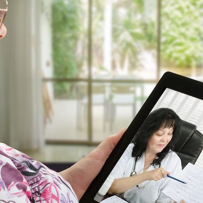 Woman communicates with telemedicine doctor by digital tablet