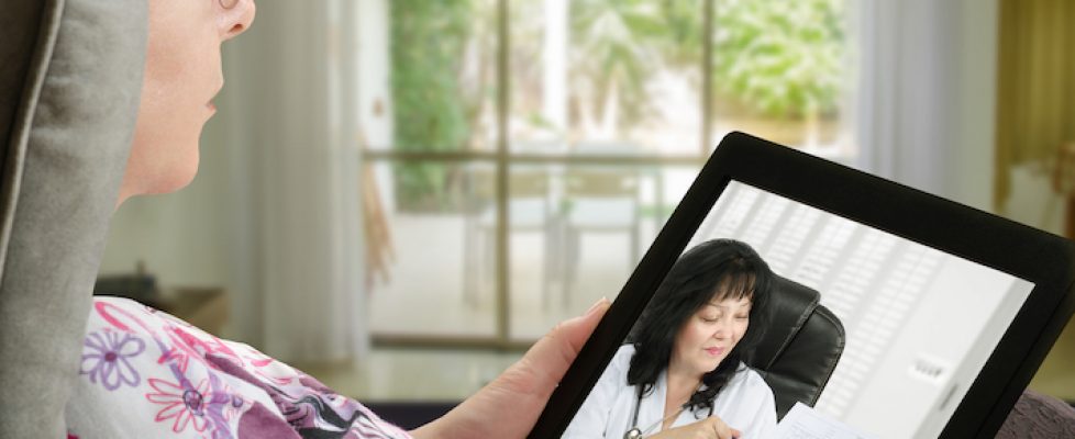 Woman communicates with telemedicine doctor by digital tablet