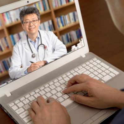 An Asian Doctor Who Is Remotely Consulting With A Patient. Teleh