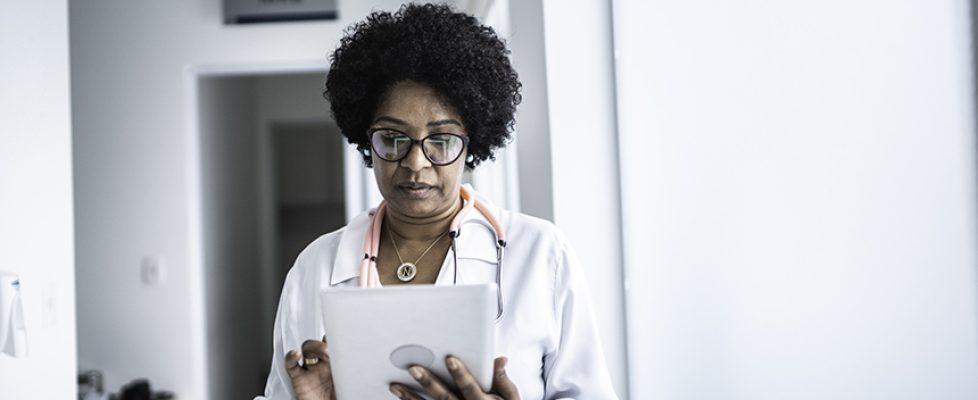 Mature female doctor using digital tablet at medical office